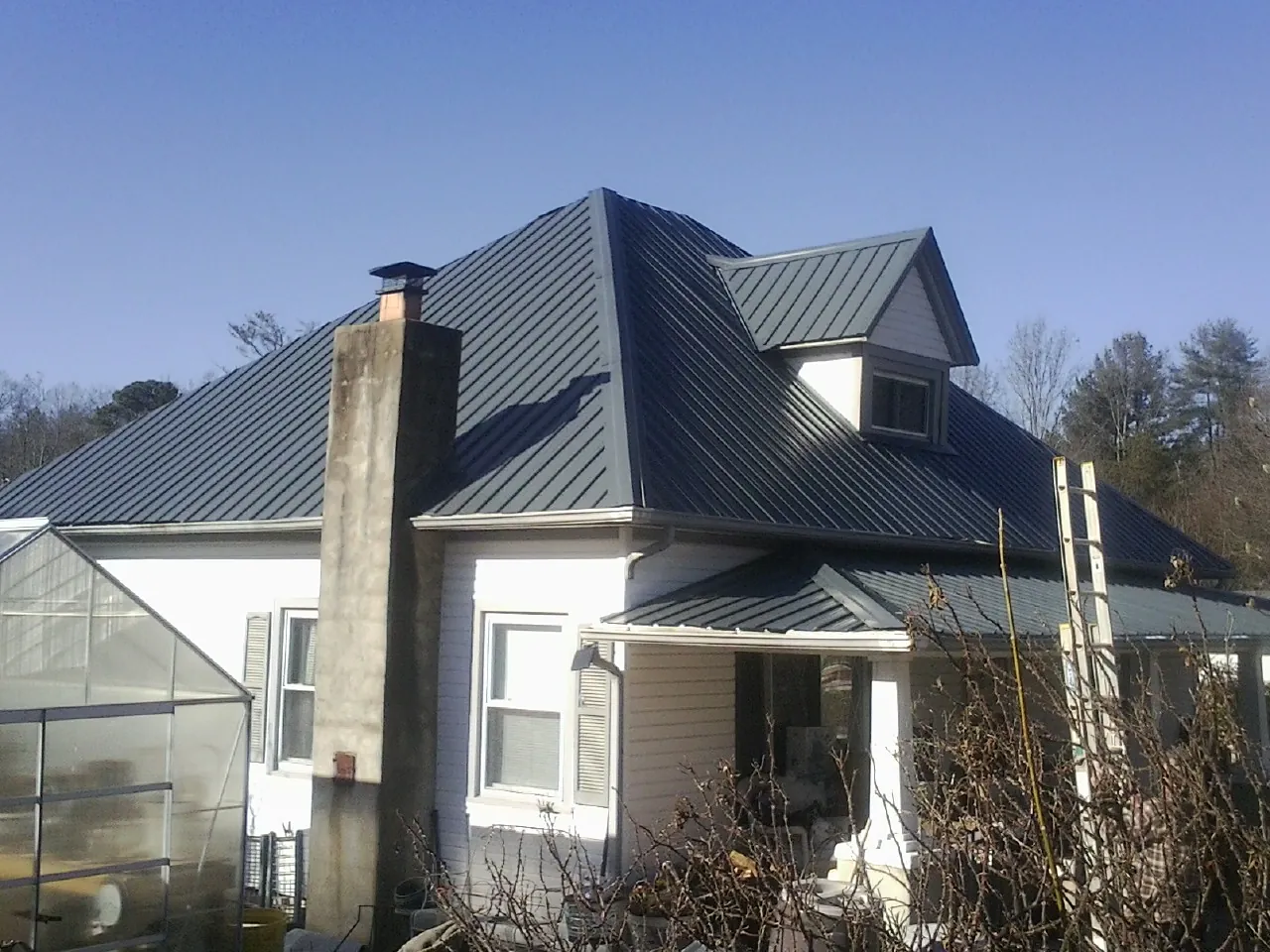 Dark blue standing seam metal roof on a white farmhouse with dormer — Slate & Tile Roof Repair by Roofing Brothers in Beavertown