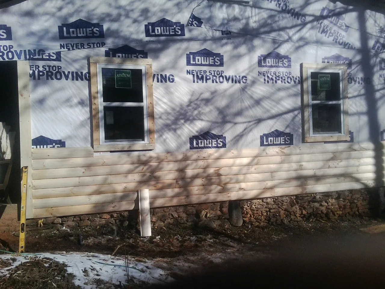 House wrap and new log siding going up on an exterior wall in Beavertown