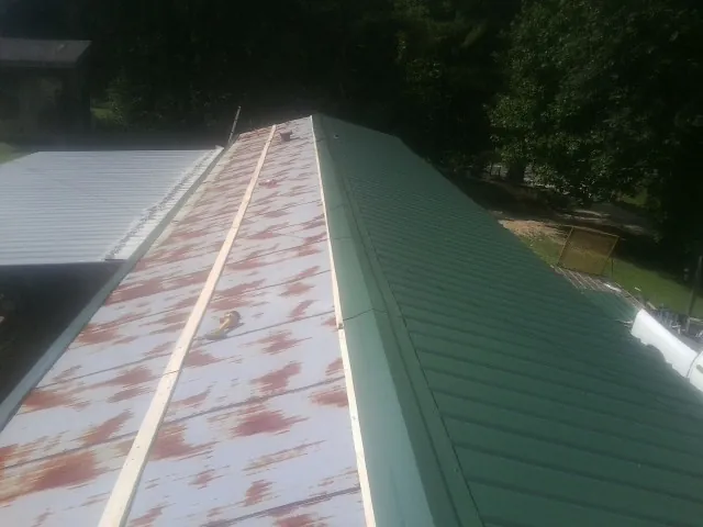 Old rusted panels beside newly installed green metal roofing — Wind Damage Roof Repair by Roofing Brothers in Beavertown