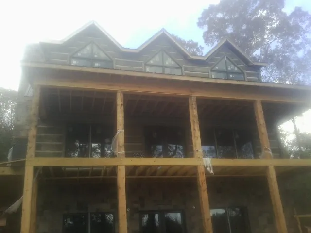 Dormers and porch framing on a large log home under construction — Roof Coating work by our crew in Beavertown