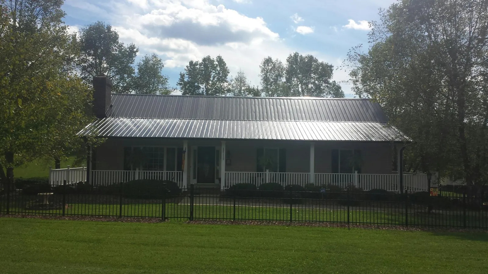 Gray metal roof on a brick ranch with a full width front porch — Gutter Guard Installation work by our crew in Beavertown