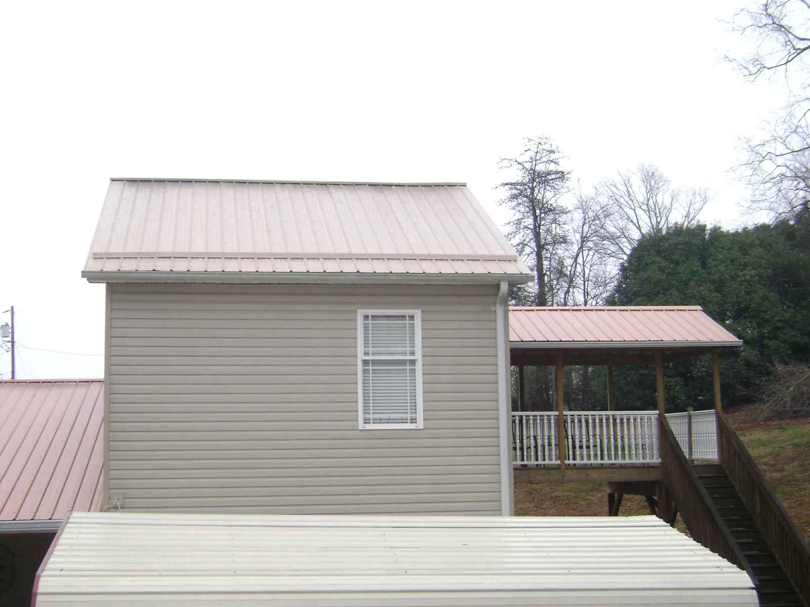 Tan metal roofs on a two story addition and attached porch, from a Roof Replacement job in Beavertown