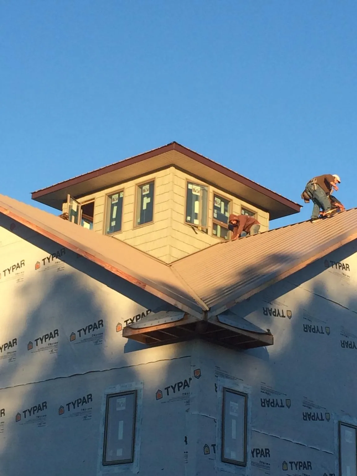 Roofers working around a rooftop cupola on a new metal roof at sunset — Roof Waterproofing in Beavertown by Roofing Brothers